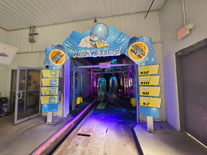 Wash Wizzard tunnel entrance with pricing signs and colorful branding